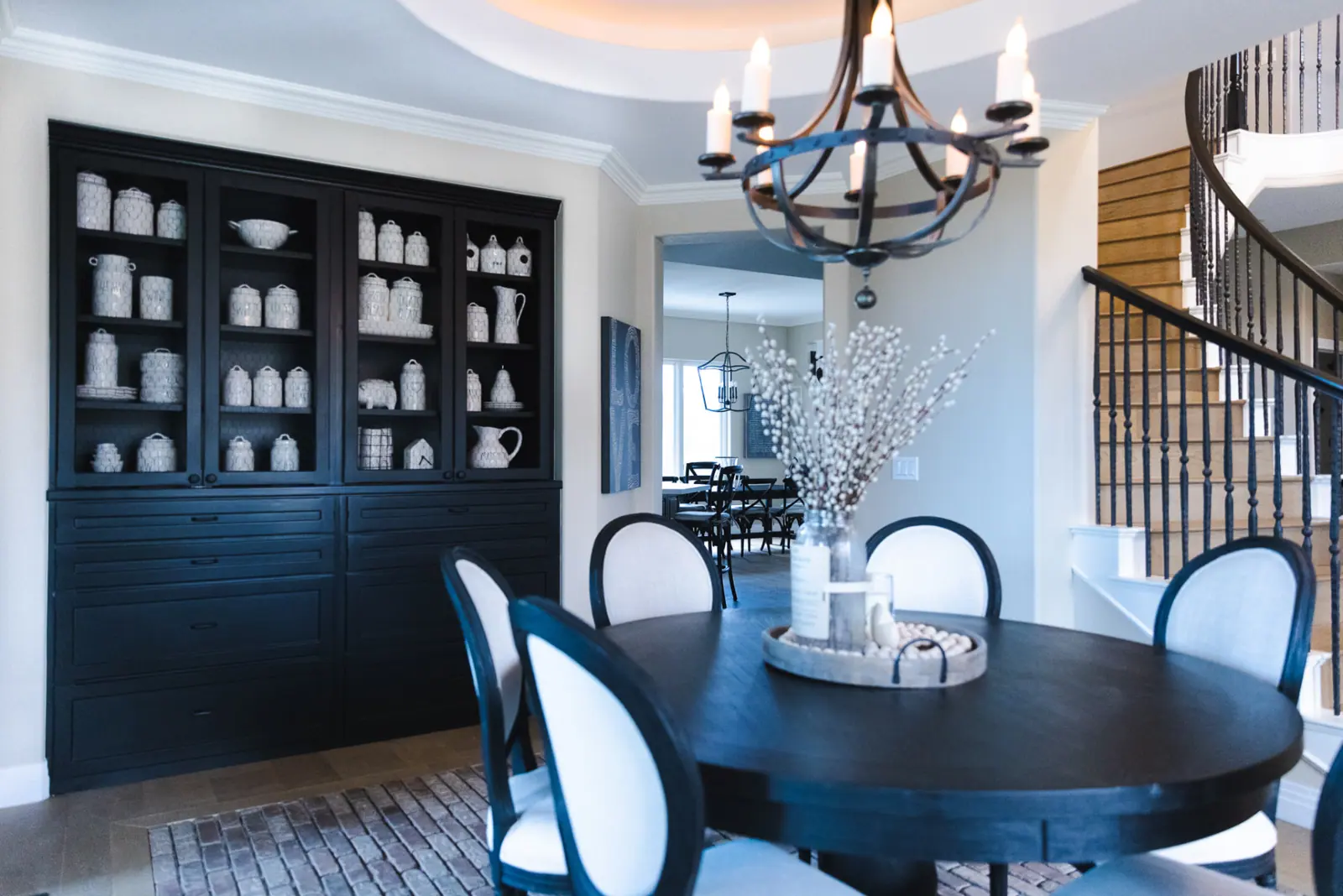 The same built-in hutch painted deep black and styled with white pottery in a soft gray dining room