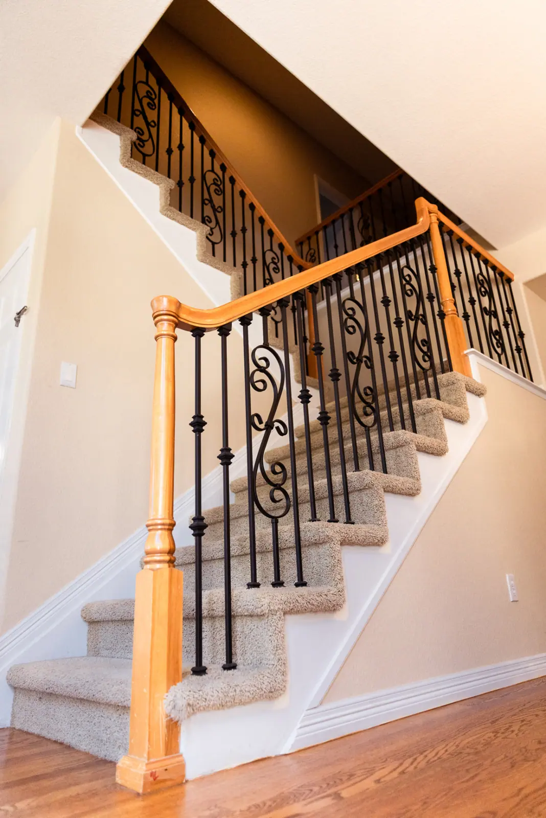 Neutral stairwell with white trim and black iron railing