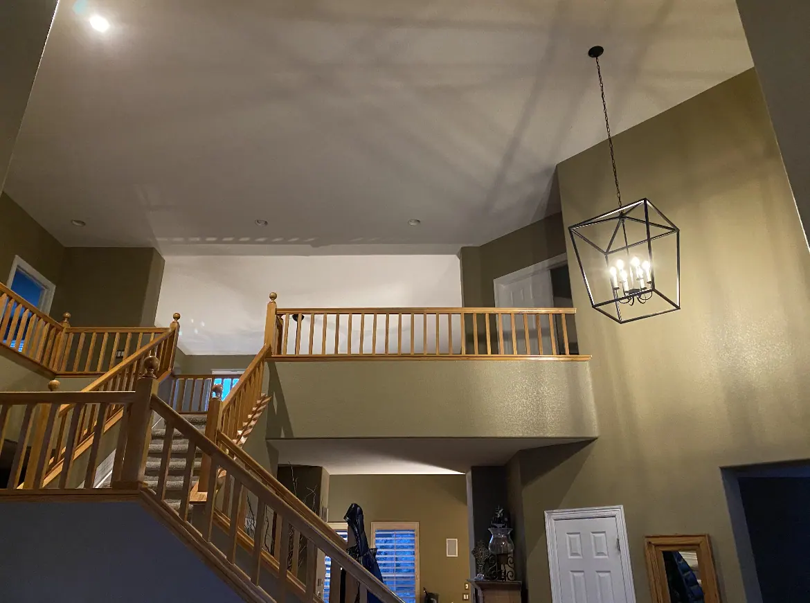 Two-story stairwell with olive walls and honey oak railings and spindles before painting