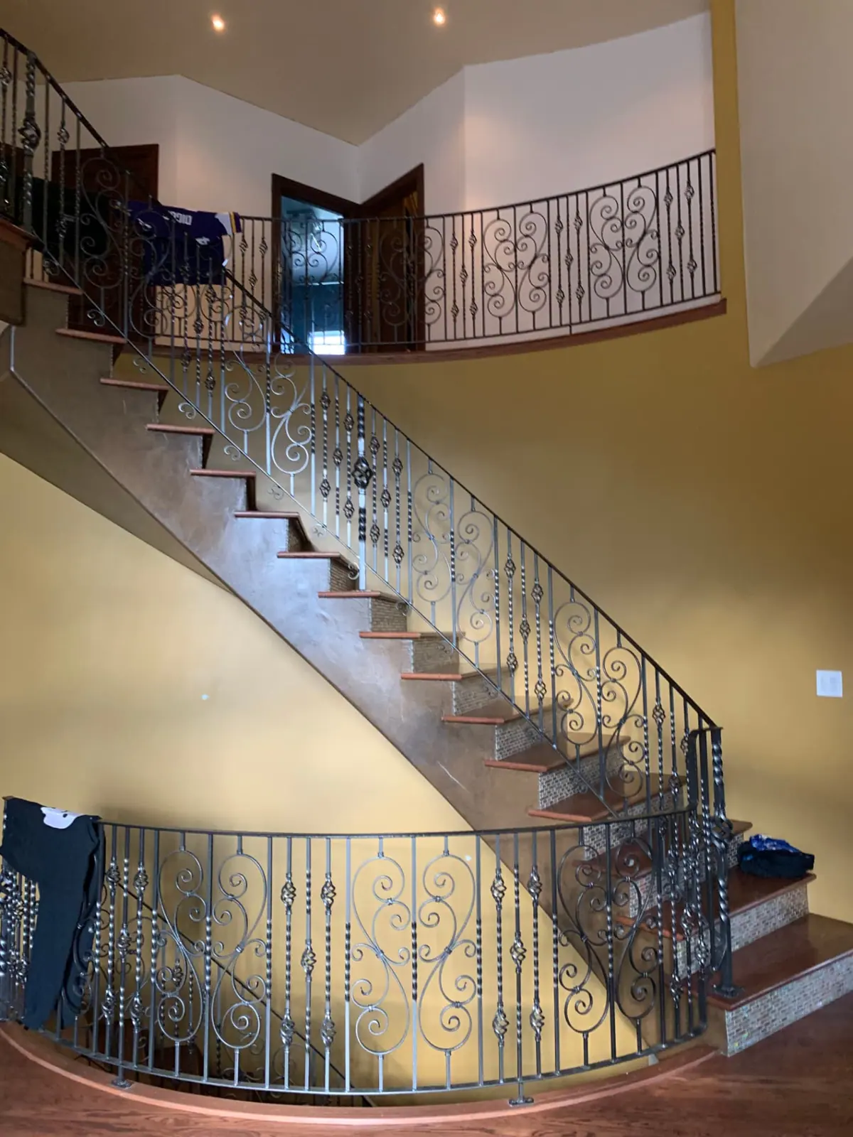 Curved staircase with tan walls and heavy textured ceilings before painting