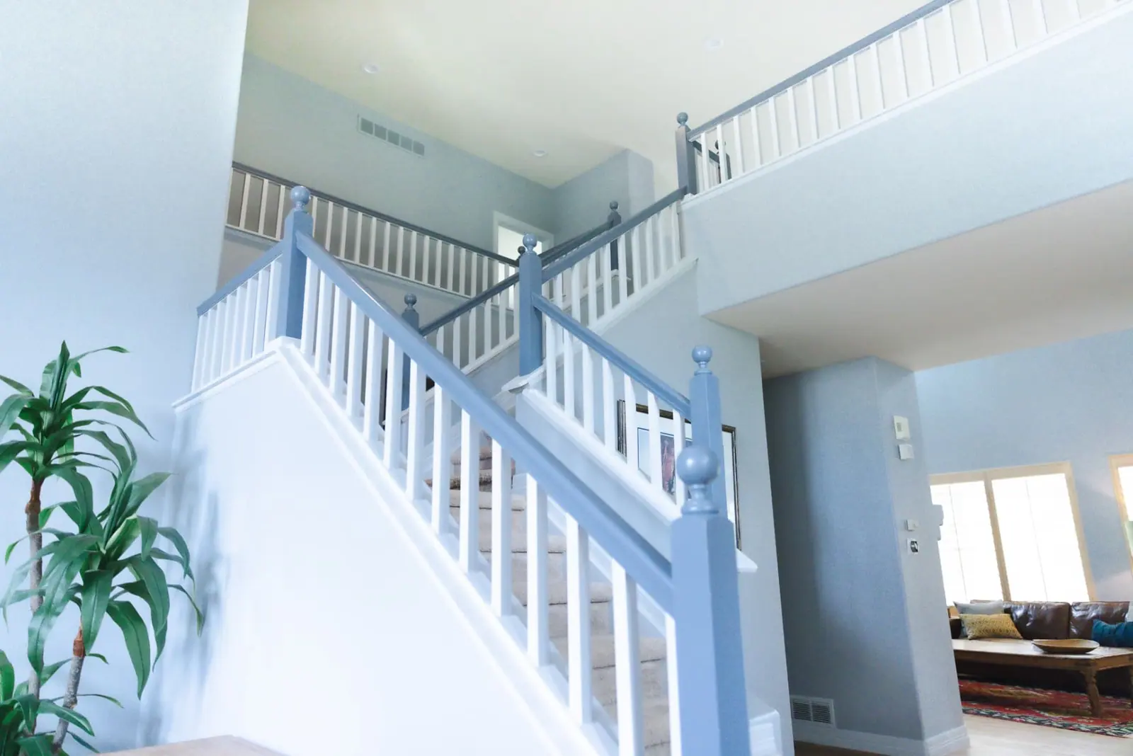 The same stairwell repainted with soft blue-gray walls, white spindles and slate-blue handrails